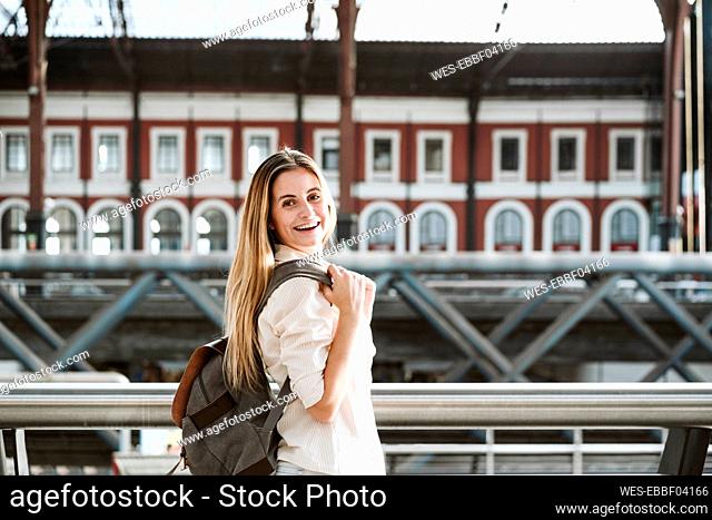 Happy blond woman wearing backpack st railroad station