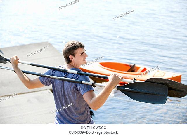 Young man holding canoe oars on shoulders