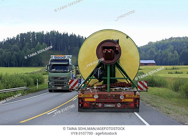 Rear view of oversize load transport by semi trailer of Peter-Star, Poland, passing a special transport truck on road. Salo, Finland - July 27, 2018