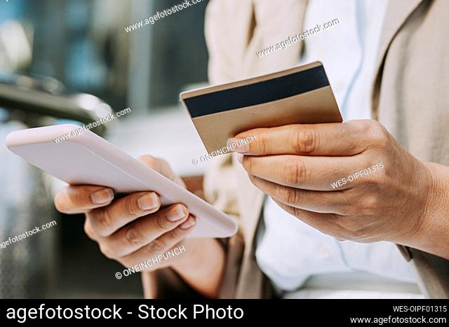 Woman doing online payment through credit card while using smart phone