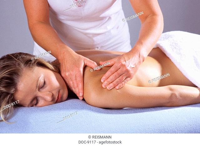 Young adult woman is massaged in the neck and shoulder