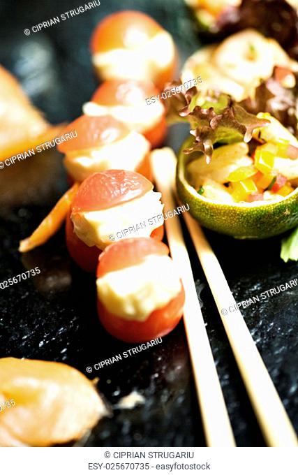 Cherry tomatoes filled with delicious blue crem cheese, served on a platou with lime baskets filled with chopped vegetables, fruits and fish