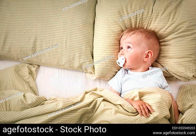 One year old baby lying in the bed with green bedding