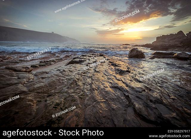 Sunset in Tagle beach. panoramic view of nice colorful huge cliff and sea on the back. Cantabria. Spain