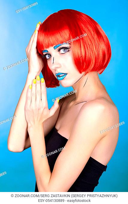 Portrait of young woman in comic pop art make-up style. Female in red wig on blue background