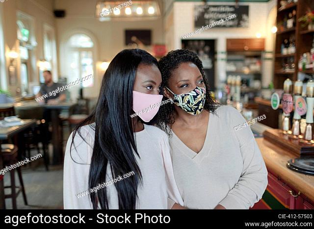 Mother and daughter in face masks in pub