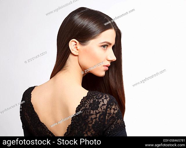 Back view closeup picture of beautiful woman with modern hairstyle in studio. Pretty female in black dress showing her back