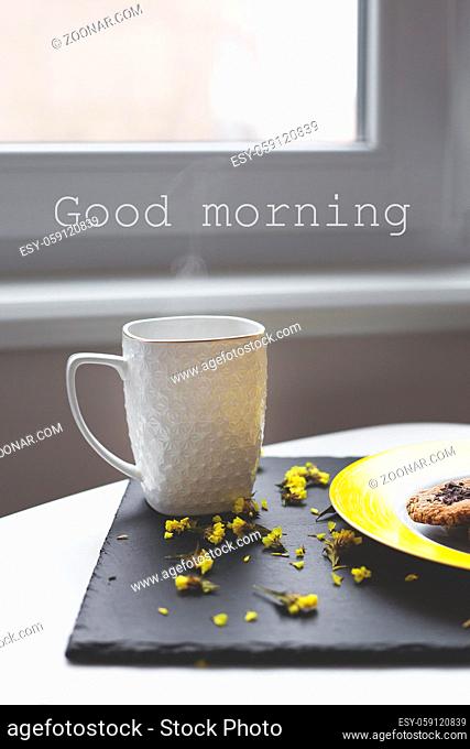 Oatmeal cookies with chocolate on bright yellow plate and cup of coffee, good morning inscription