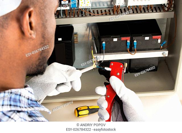 Close-up Of Young African Electrician Stripping Electrical Wires