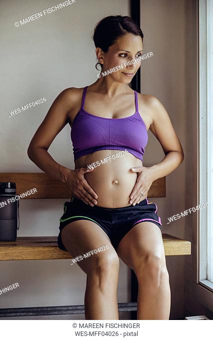 Sporty pregnant woman sitting in locker room