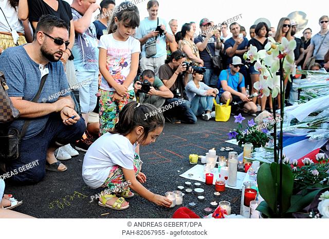 A girl places a candle at the scene in Nice, France, July 15, 2016 where a lorry drove into a crowd during Bastille Day celebrations