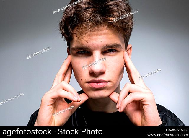 Wide angle. Studio shot. Young caucasian guy model in black clothes posing in the studio. Teenager in Leather Jacket Standing Against White Background
