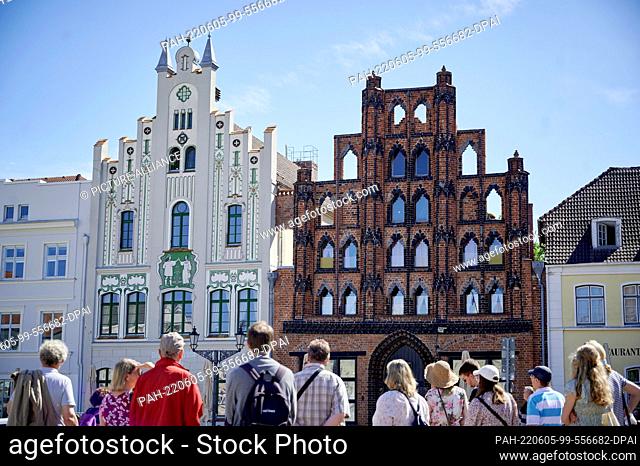 05 June 2022, Mecklenburg-Western Pomerania, Wismar: A group of tourists stands in front of the historic gabled houses on the market square in Wismar