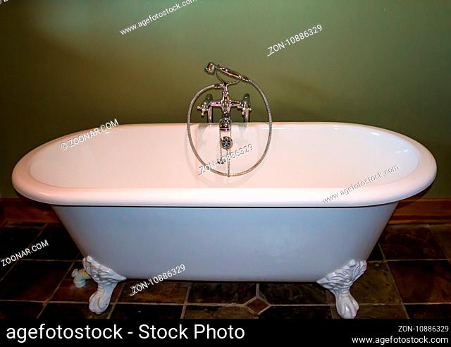 White luxury roll top bath tub against olive green background