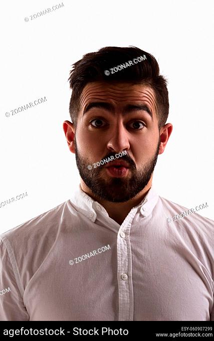 Portrait of surprised handsome hipster man looking at camera isolated on white background. Bearded man in white shirt in studio. Emotions concept