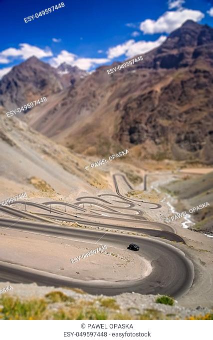 Car driving uphill on the twisting and turning switchback road through high Andes in Chile, South America
