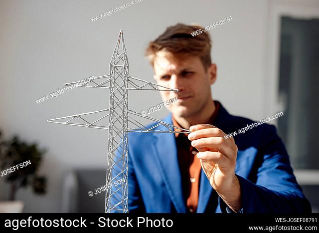 Businessman looking at electricity pylon model in office