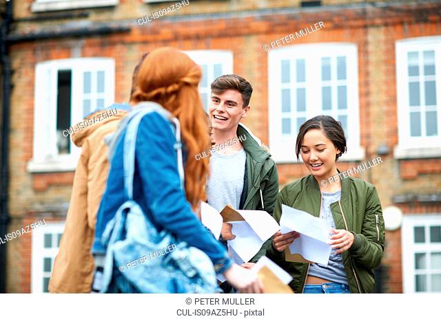 Happy male and female college students reading exam results on campus