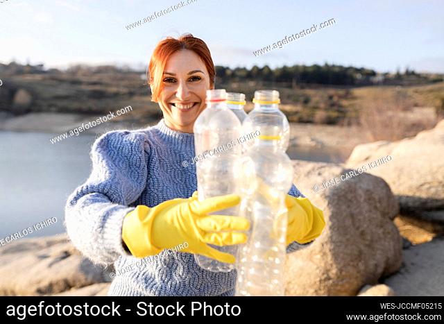 Smiling environmentalist showing plastic bottles at beach