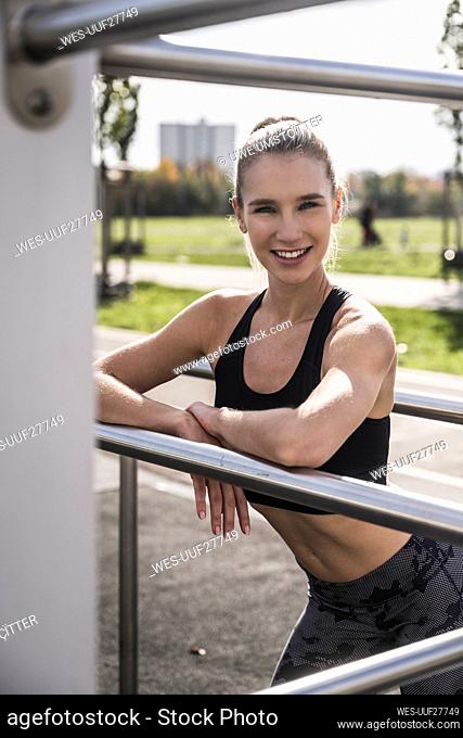 Smiling sportswoman standing by horizontal bar