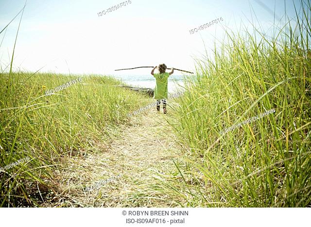 Female toddler carrying long stick