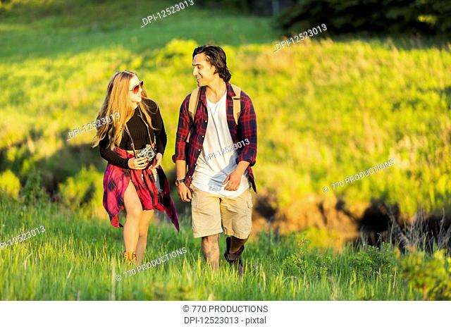 Young couple walking together in a city park; Edmonton, Alberta, Canada
