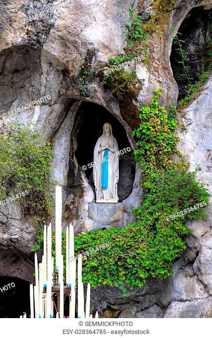 LOURDES, FRANCE - JULY 23, 2014: The rock cave at Massabielle with the statue of the Virgin Mary where Saint Bernadette Soubirous claimed to have witnessed...