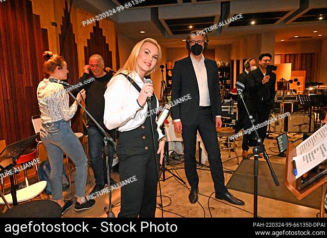 24 March 2022, Bavaria, Tutzing: Ukrainian pop singer Kamaliya sings in a Tutzing recording studio. Standing to her right is Bavarian Culture Minister Markus...
