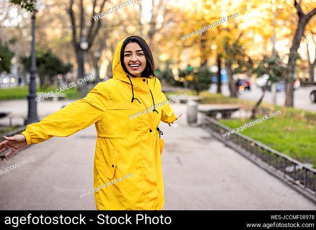 Carefree young woman with arms outstretched enjoying at park