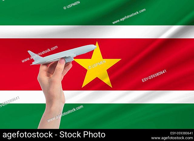 Airplane in hand with national flag of Suriname. Travel to Suriname