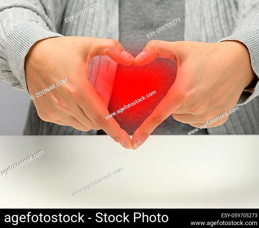 two female hands folded in the shape of a heart on a white background. Gratitude and kindness concept, copy space