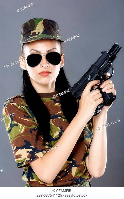 Female soldier in camouflage uniform with weapon isolated on gray background