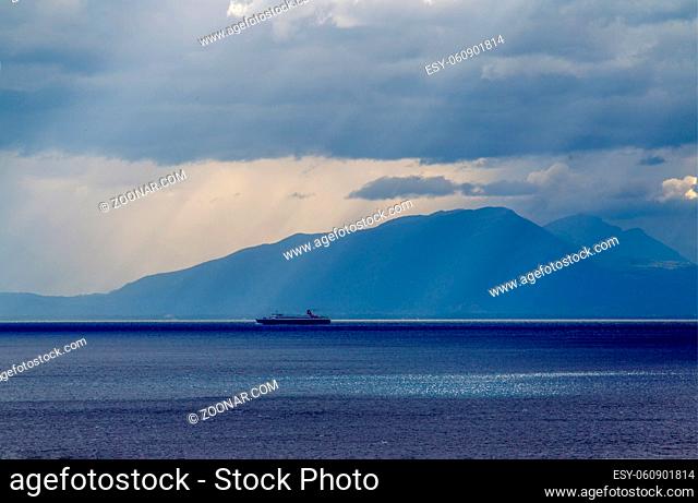 Idyllic seascape in Tyrrhenian sea . Ship moving to cargo port Salerno. And mountain coast of Campania. View from Amalfi coast
