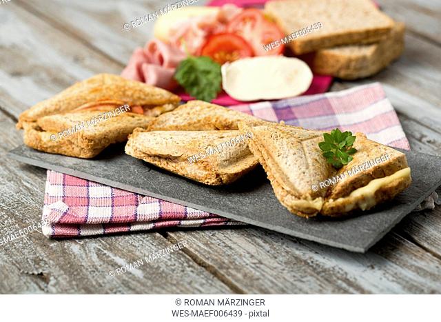 Ham and cheese sandwich with tomatoes on chopping board