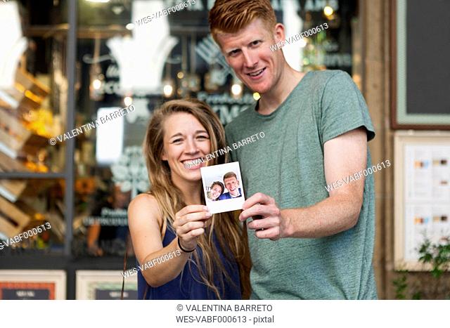 Happy couple showing selfie of their wedding in front of a coffee shop