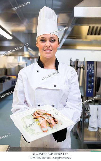 Smiling chef showing her plate in the kitchen