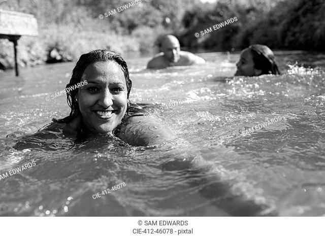 Portrait happy woman swimming with family in sunny river