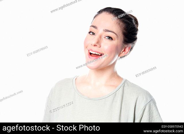 joyful young woman in her 20s with natural make-up and brunette hair bun smiling - isolated on white background