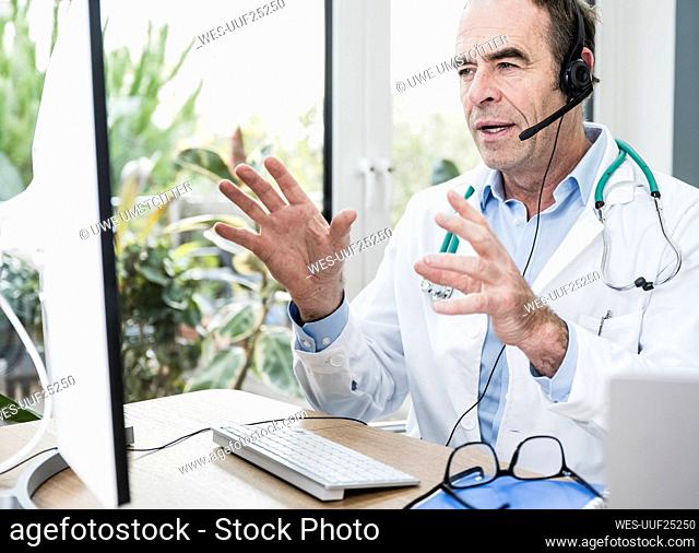 Doctor talking through headset on video call at office