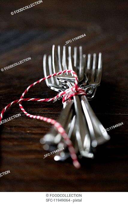 Forks tied with string on a wooden surface