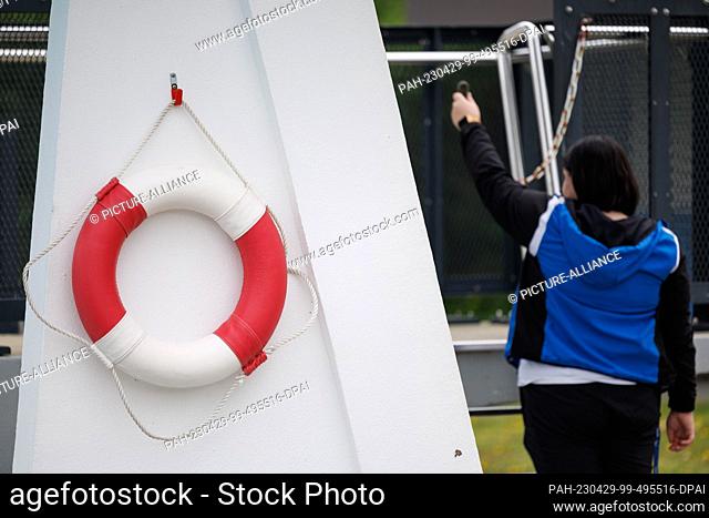 28 April 2023, North Rhine-Westphalia, Paderborn: ILLUSTRATION In a posed situation, a pool attendant opens the chain from a diving tower at the Rolandsbad...