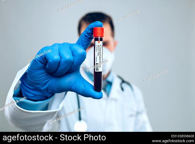 Doctor wearing respiratory mask and holding the Coronavirus Covid-19 blood sample