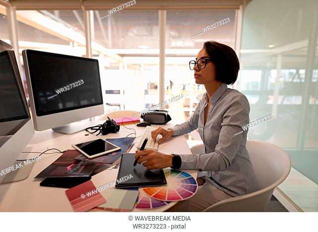 Graphic designer working over graphic tablet at desk in office