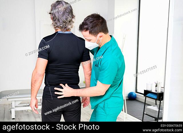 Rear view of a physiotherapist examining man back. High quality photo