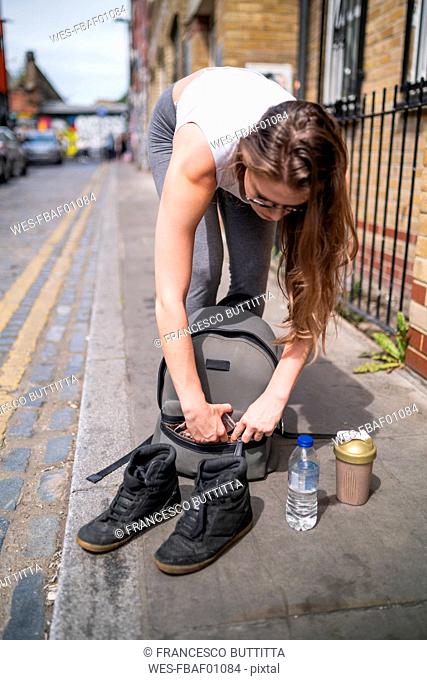 Young woman packing her backpack in the city