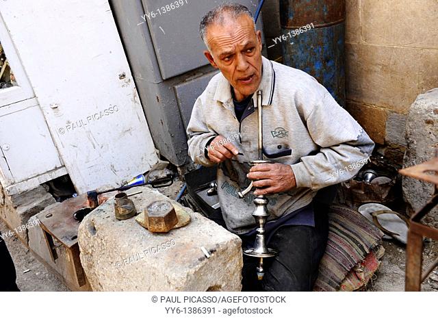 egyptian man cleaning shisha pipes sheesha , a traditional past time in egypt and the middle east , islamic cairo , street scene , cairo , egypt