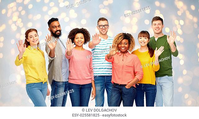 diversity, race, ethnicity and people concept - international group of happy smiling men and women waving hand over holidays lights background