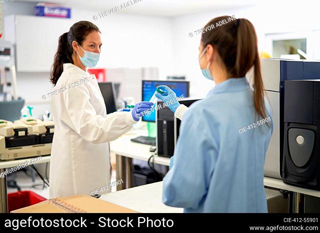 Female scientists in face masks holding specimen in laboratory