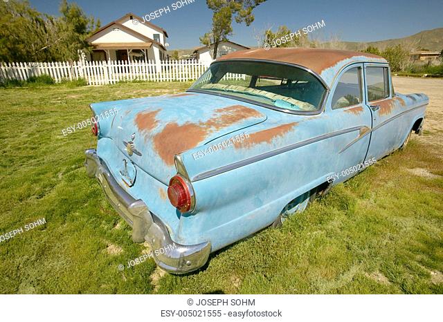 An antique abandoned 1955 Ford in front yard of house near Barstow, CA off of Route 58