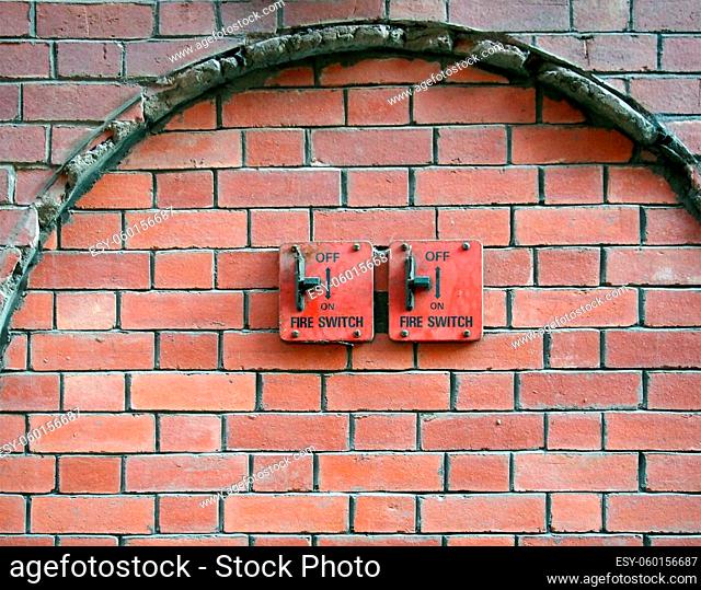 two old red metal fire switches on an exterior brick wall